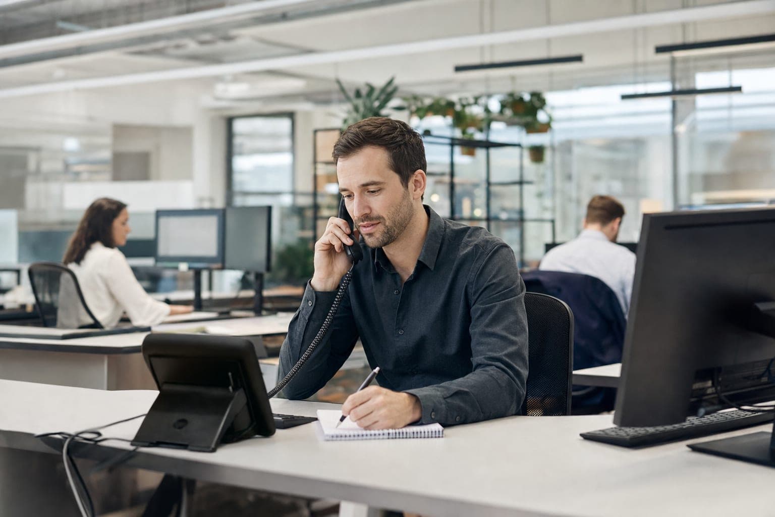 Recruiter im Büro am Telefon, daneben Notizblock und Tischapparat
